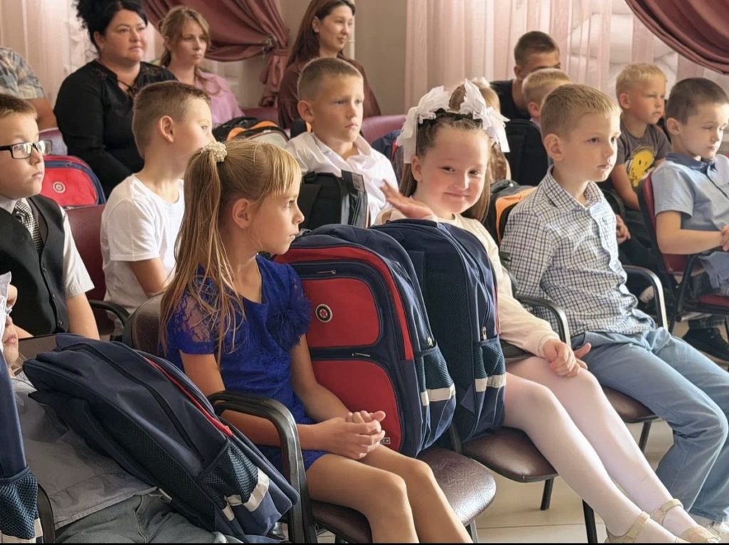 Дети сидят в зале с новыми школьными рюкзаками